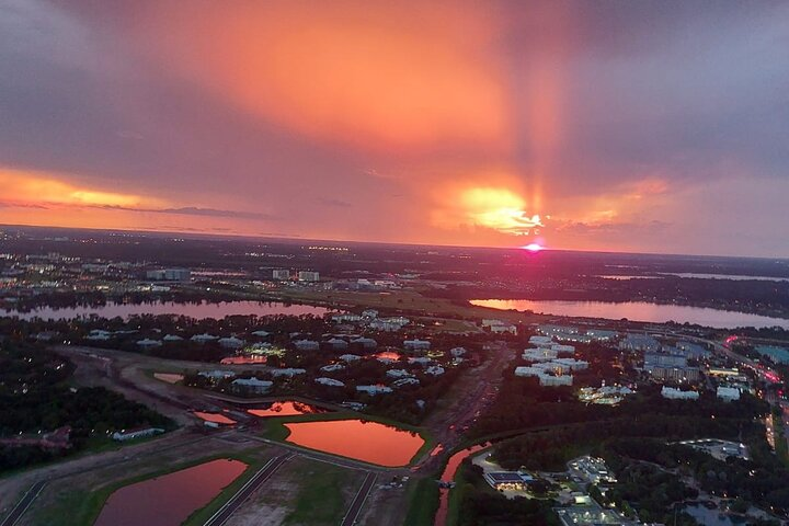 Experience the magic of Central Florida as the sun sets illuminating iconic parks and attractions from above. A serene helicopter ride reveals a stunning panorama of glistening lights below.